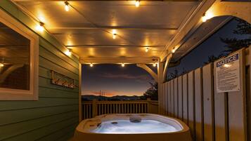 A hot tub area with a sunset view, a wooden deck, and a safety notice sign.