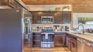 A modern kitchen with stainless steel appliances, wooden cabinets, and a granite countertop.