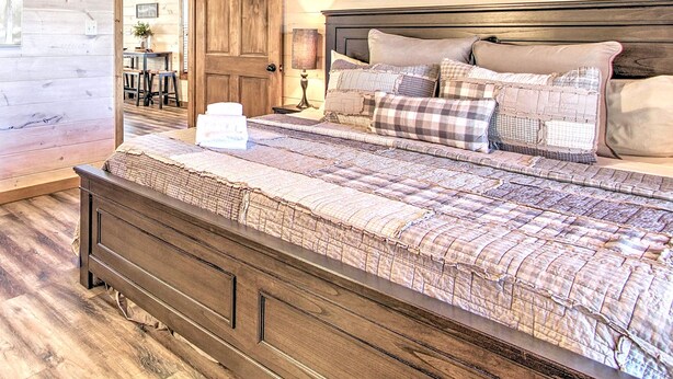 A wooden-paneled bedroom with a bed, a nightstand, and a framed picture on the wall. - All Decked Out in Pigeon Forge (Pigeon Forge)