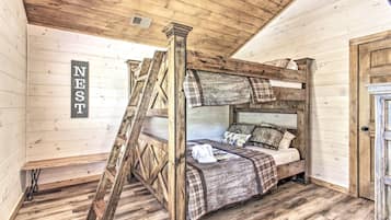 A rustic wooden room with a loft-style bed, a ladder, and a sign that reads 'NEST'.