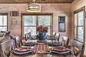 A wooden cabin interior with a dining table set for six, surrounded by wooden chairs. - All Decked Out in Pigeon Forge (Pigeon Forge)