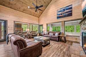 Un salón comedor amplio con chimenea, muebles de cuero y grandes ventanales con vistas al exterior.