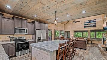 A spacious kitchen with modern appliances, a large island, and a dining area with a stone fireplace.