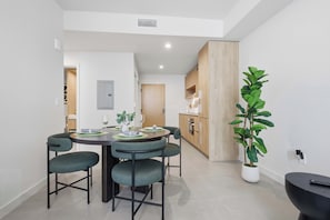 A modern dining area with a round table, four chairs, and a potted plant. - The Crosby Luxury 1BR/1BA in Downtown Miami | 710 (Miami)