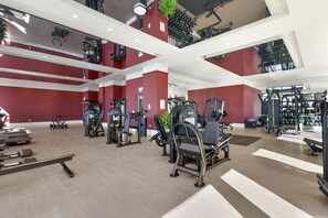 A modern gym with various exercise equipment, a high ceiling, and red walls. - The Crosby Luxury 1BR/1BA in Downtown Miami | 710 (Miami)