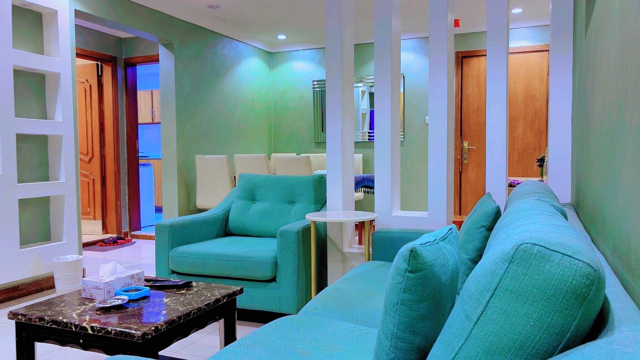 A modern living room with teal sofas, a coffee table, and a small side table.