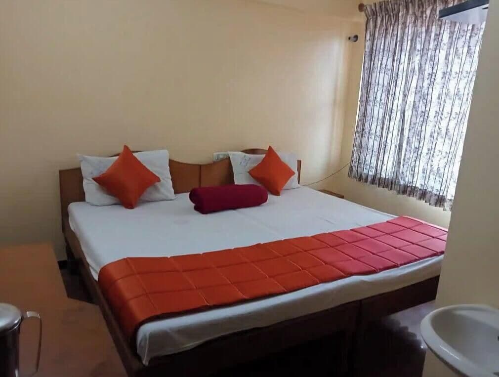 A bed with a white and orange bedspread, two pillows, and a red blanket.