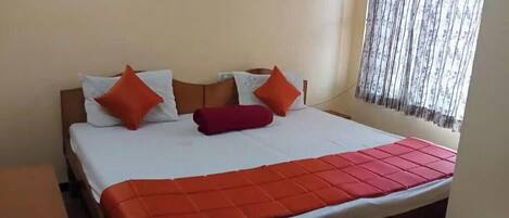 A bed with a white and orange bedspread, two pillows, and a red blanket.