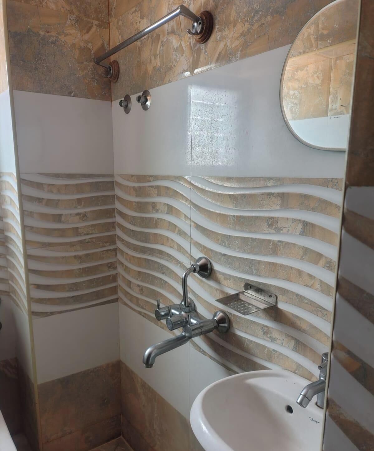 Ein Badezimmer mit einer Duschwand im Bogen, einem weißen Waschbecken und einem Spiegel.
