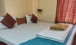 A bed with a blue bedspread, two brown pillows, and a folded blanket. - Hotel Royal Park (Coimbatore)