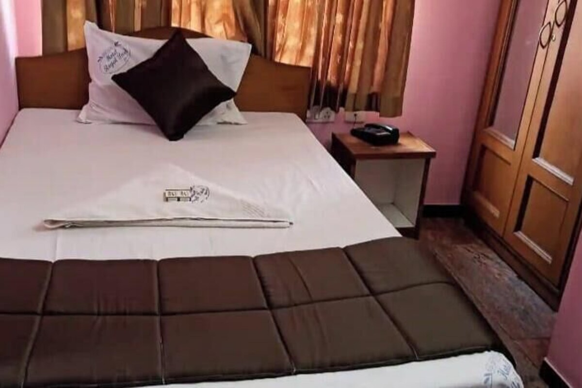 A bed with a headboard, a bedside table with a lamp, and a wardrobe.