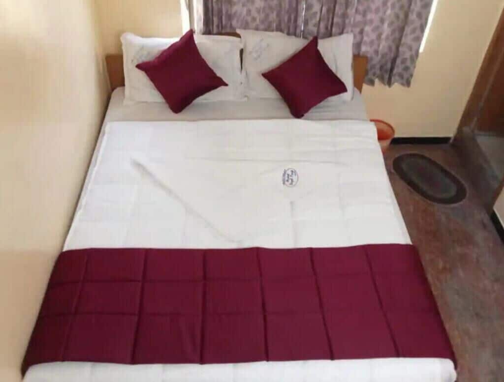 Ein Bett mit einer weißen und purpurfarbenen Bettdecke, zwei purpurfarbenen Kissen und einem kleinen Logo in der Mitte.