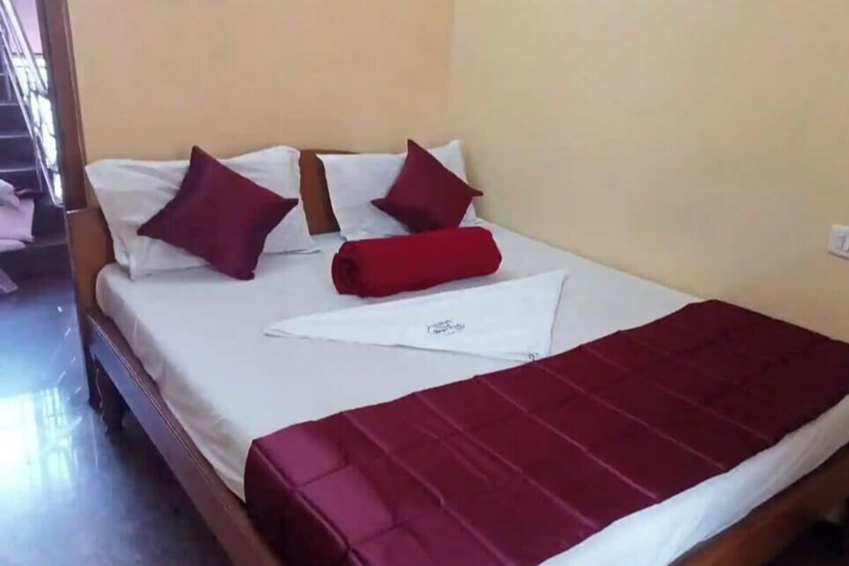 A hotel room with a bed, pillows, and a blanket.