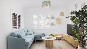 A modern living room with a sofa, a coffee table, a TV, and a large plant. - Sandy Toes Haven a Lux Pet-Friendly Retreat (Nelson Bay)