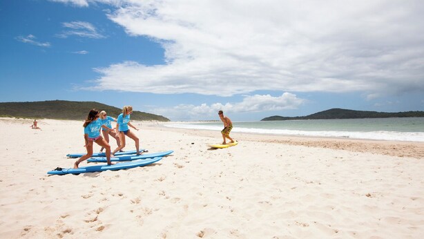 Une plage où l’on voit des gens sur des planches de surf.