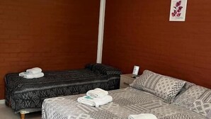 A hotel room with a bed, a sofa, and an air conditioning unit.