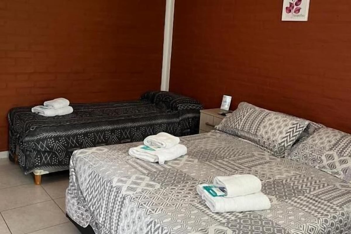 A hotel room with a bed, a sofa, and an air conditioning unit.