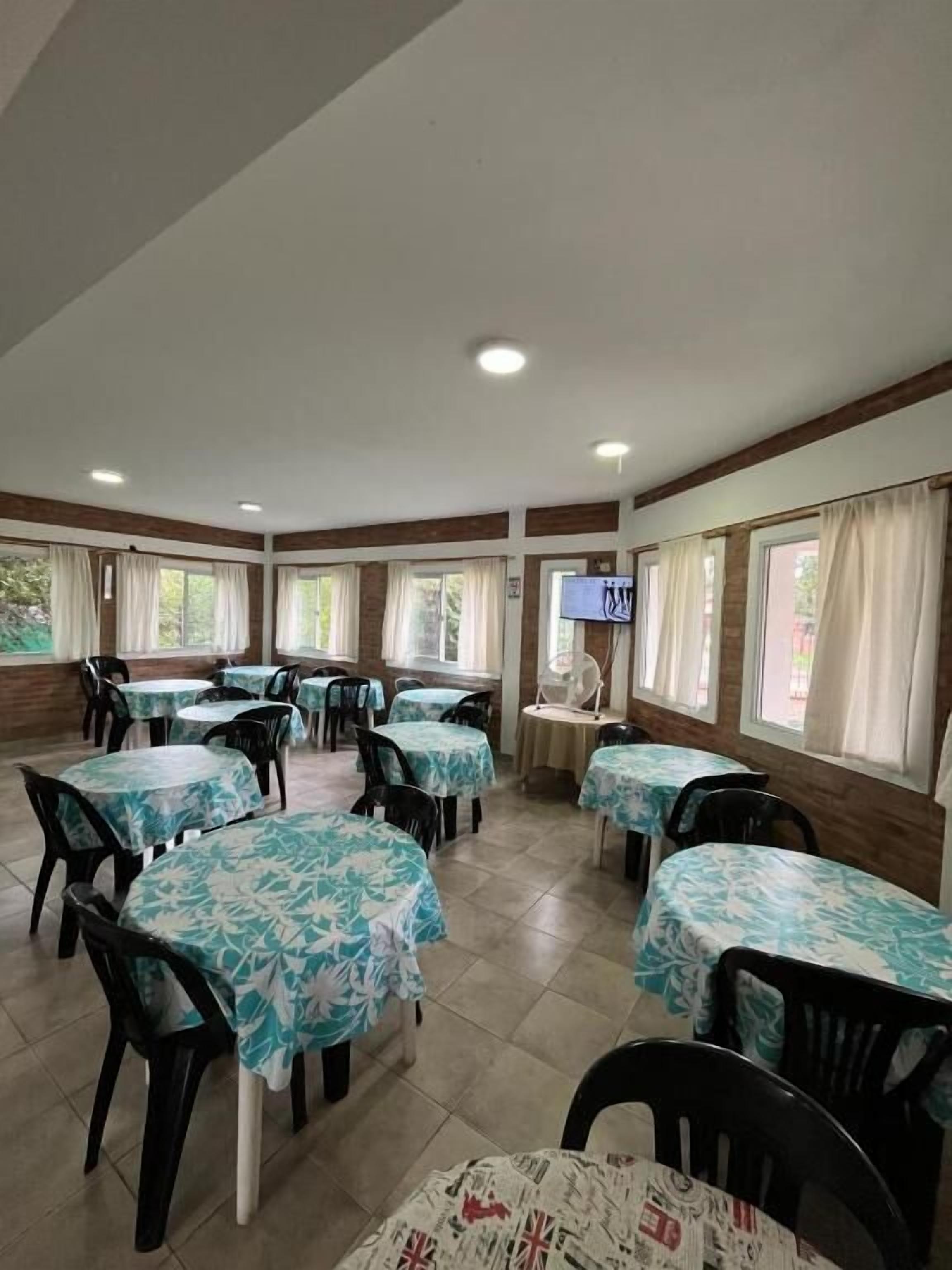 A dining area with round tables, chairs, and a television screen.