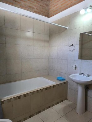 A bathroom with a bathtub, a sink, and a mirror. - Hotel Aimara  (Mina Clavero)