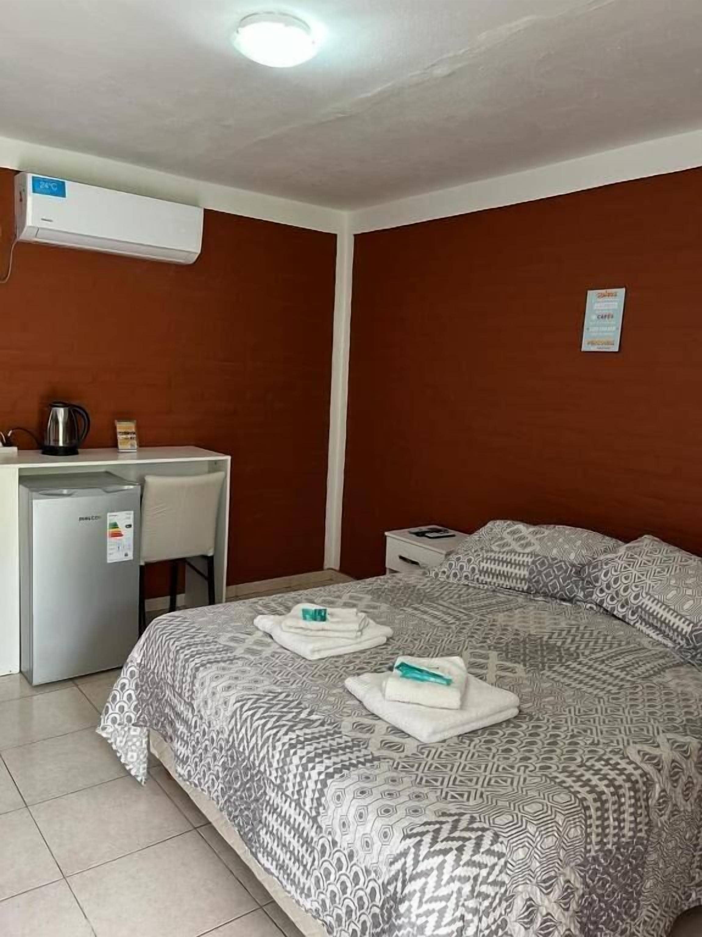 Une chambre d’hôtel équipée d’un lit, d’un bureau avec une bouilloire et d’un appareil de climatisation.