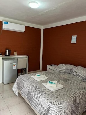 A hotel room with a bed, a desk with a kettle, and an air conditioning unit. - Hotel Aimara  (Mina Clavero)