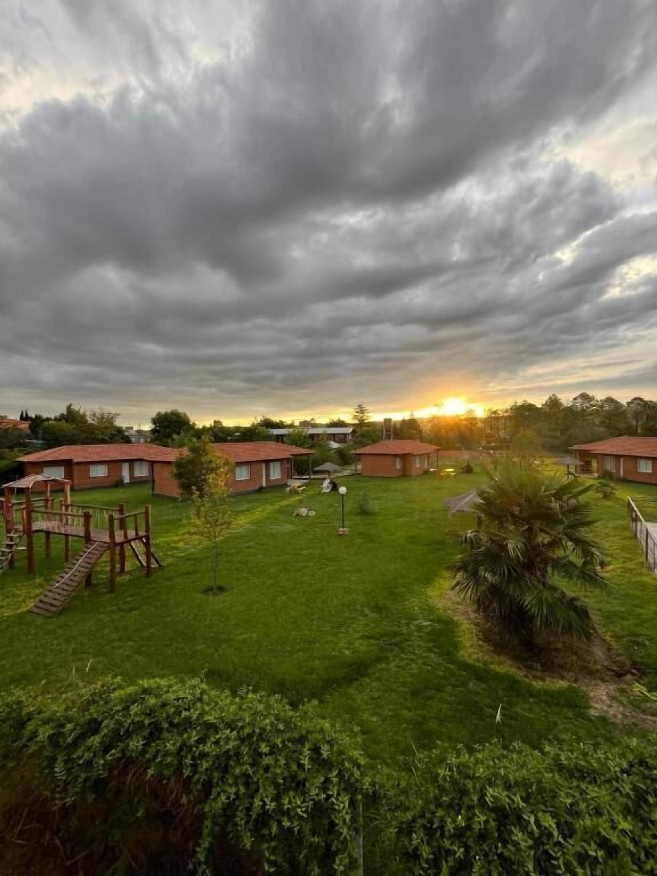 Un barrio residencial con varias casas de techo rojo, un jardín césped y un parque infantil.