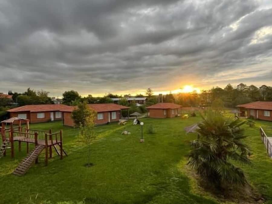 Un barrio residencial con varias casas de techo rojo, un jardín césped y un parque infantil.