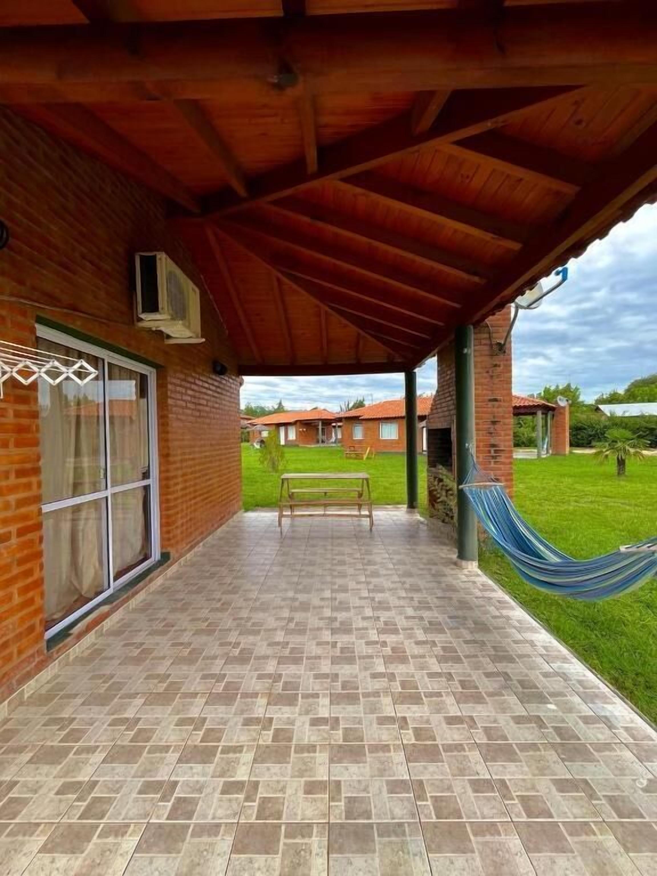 A covered patio with a brick floor, a hammock, and a bench.