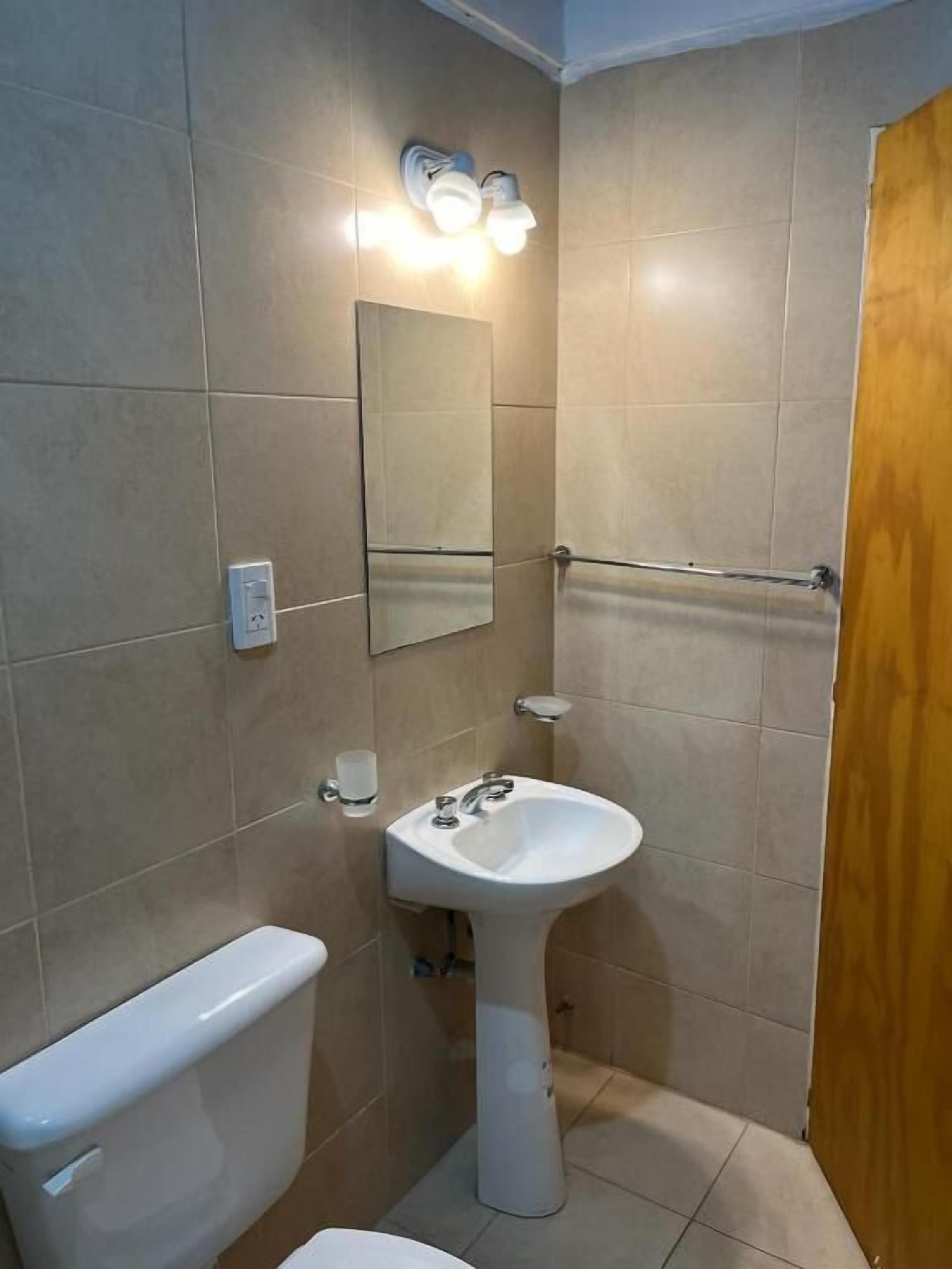 Un baño con inodoro, lavabo, espejo y toallero.