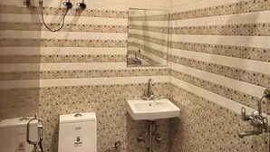 A compact bathroom with a toilet, sink, and shower. - Vida Stays (New Delhi)