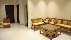 A room with a wooden bench, a small table, and a desk with a chair. - Vida Stays (New Delhi)