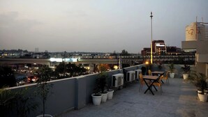 A rooftop terrace with outdoor seating, potted plants, and a view of the cityscape. - Vida Stays (New Delhi)