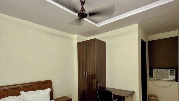 A bedroom with a bed, a desk, a wardrobe, and a ceiling fan. - Vida Stays (New Delhi)