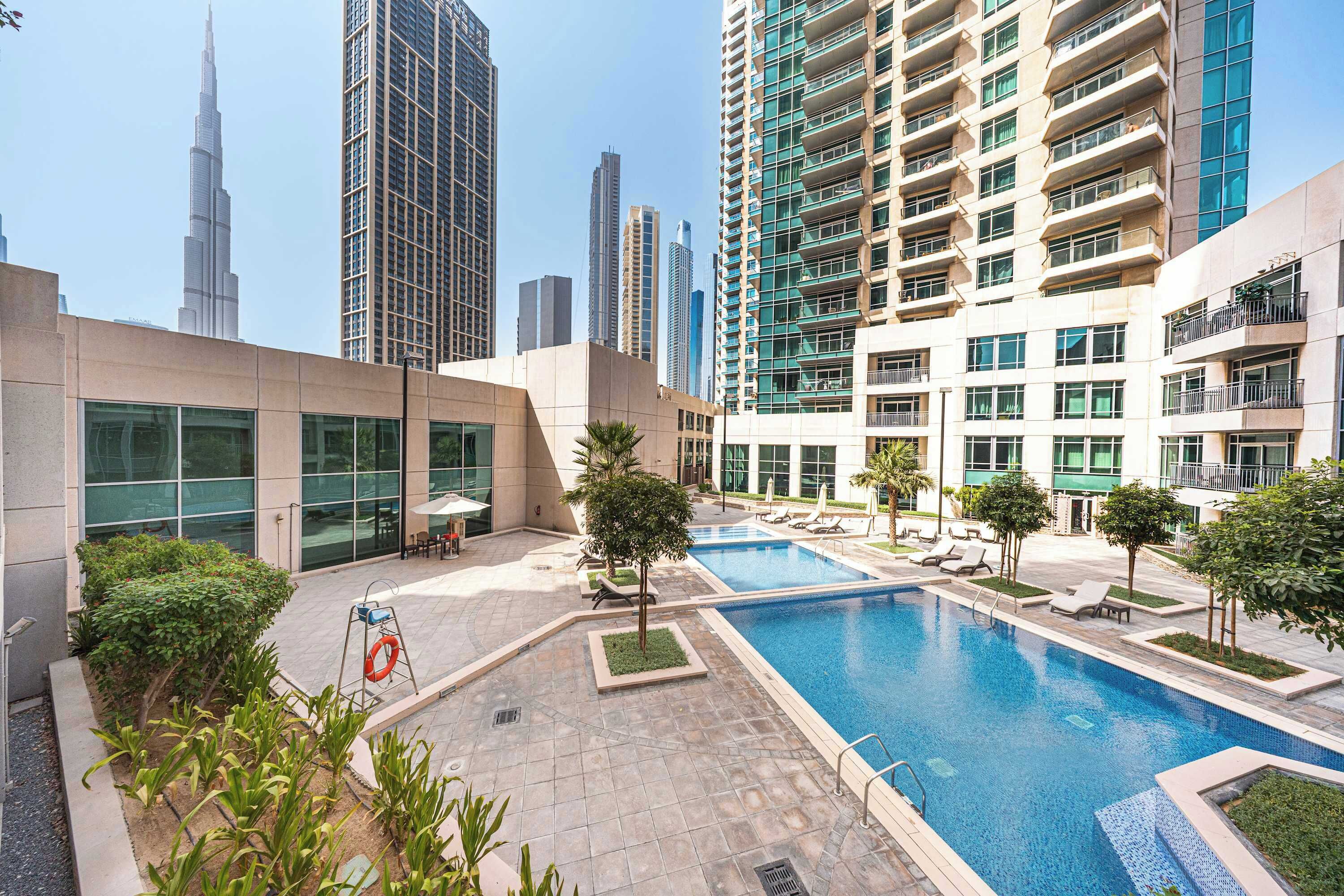 Un hotel moderno con piscina, zona de estar al aire libre y vistas a altos edificios.