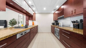 Eine moderne Küche mit Granit Arbeitsplatten, Edelstahlgeräten und Holzschränken.