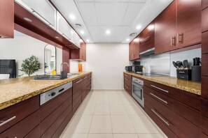 Eine moderne Küche mit Granit Arbeitsplatten, Edelstahlgeräten und Holzschränken.