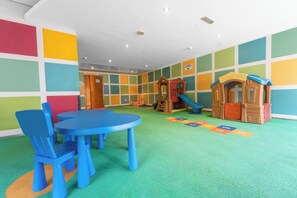 Ein Kinderspielbereich mit bunten Wänden, einem Spielhäuschen und einer Rutsche.