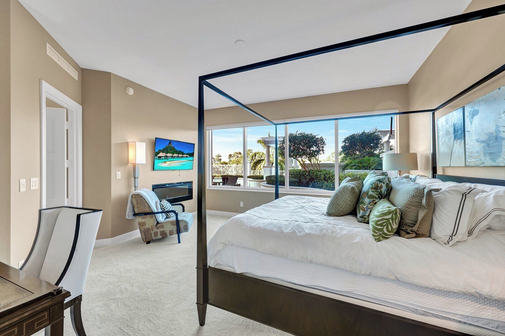 Un dormitorio con cama con dosel, televisor y vista al exterior.