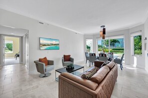 A spacious living room with a large sofa, armchairs, a coffee table, and a TV mounted on the wall. - Grande Geneva at The Dunes (Naples)