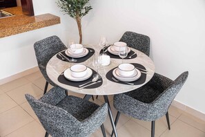 A round dining table with six chairs, each with a black and white patterned cushion. - StayShort - Luxury Studio Apartment in Downtown with Balcony (Downtown)