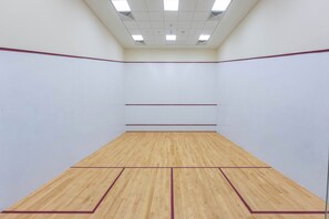 A squash court with a wooden floor and white walls, equipped with ceiling lights. - StayShort - Luxury Studio Apartment in Downtown with Balcony (Downtown)