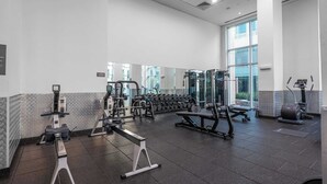 Ein modernes Fitnessstudio mit verschiedenen Trainingsgeräten, großen Fenstern und einem gefliesten Boden.