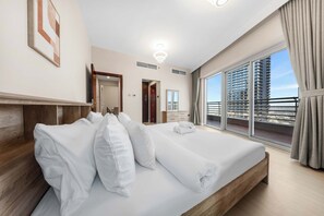 Une chambre d’hôtel avec un grand lit, une tête de lit en bois, une vue sur la ville par la fenêtre et un balcon avec une balustrade.