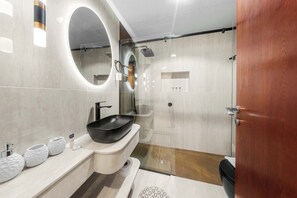 Une salle de bain moderne avec un lavabo sur pied noir, un grand miroir et un espace douche.