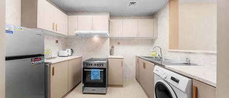 Una cocina compacta con horno integrado, lavadora y lavaplatos.