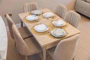 A dining area with a rectangular table set for four, surrounded by six upholstered chairs. - StayShort - Cozy 2BR Apartment in JLT that Sleeps 4! (JLT)
