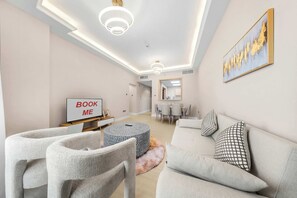 Un salon moderne comprenant un canapé, des fauteuils, un téléviseur et un coin repas.