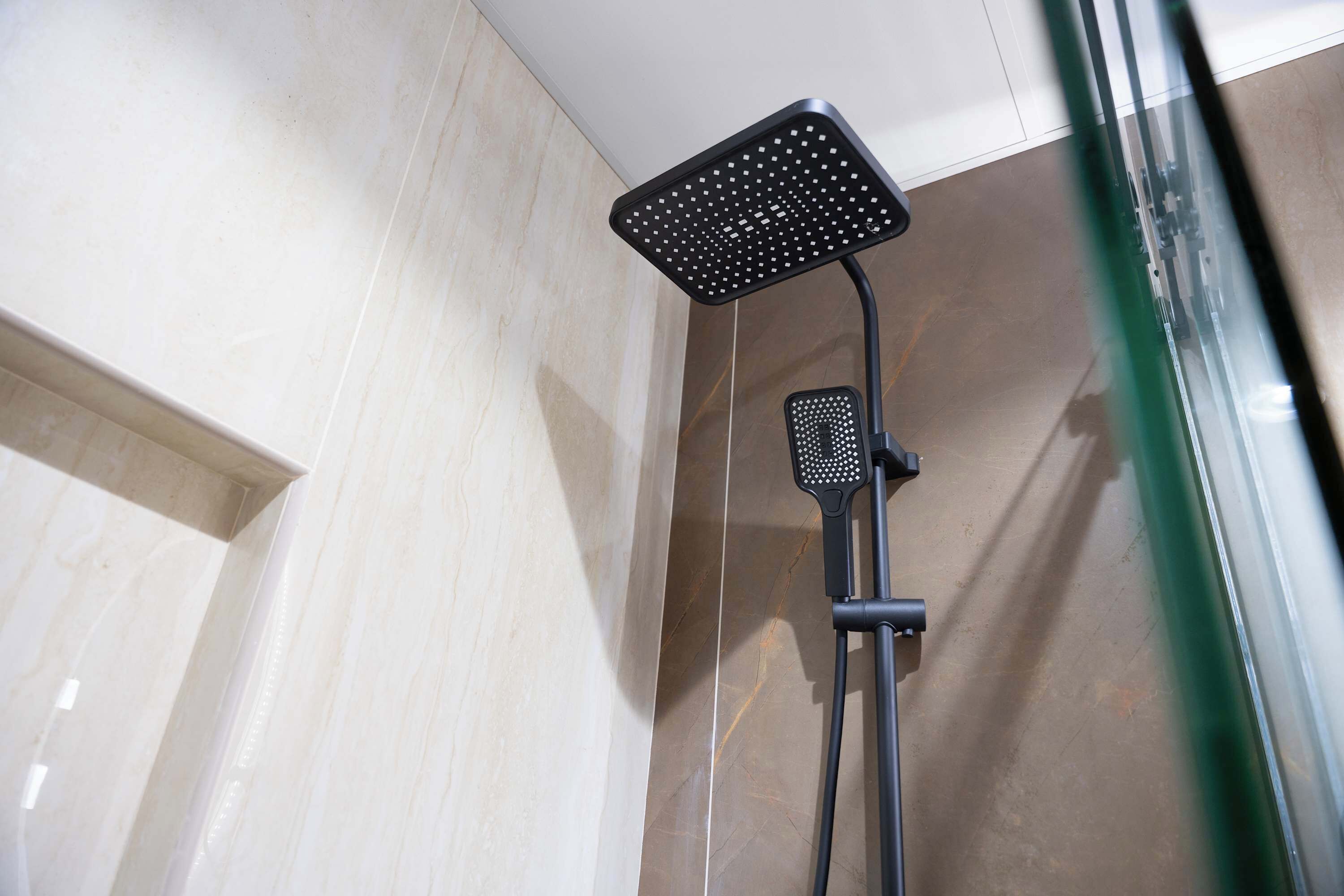 A shower with a square head and a handheld showerhead.