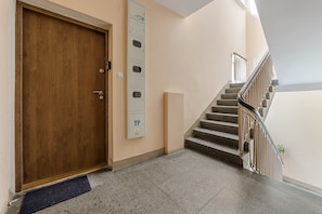 A wooden door, a wall-mounted electrical box, and a staircase with metal railings. - Lumina Family 4-room Apart near Metro  (Warszawa)