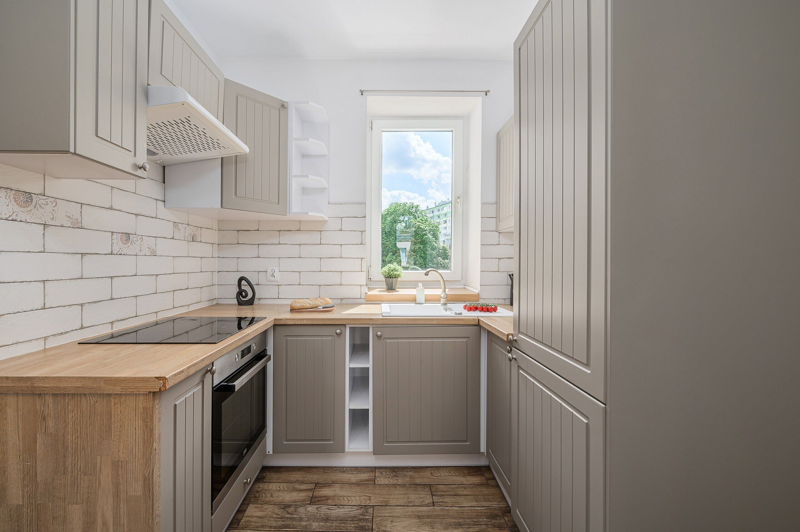 Cocina compacta con ventana, horno empotrado y lavamanos.